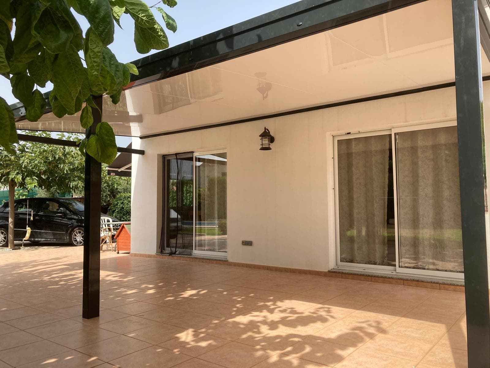Pérgola con sombra sobre terraza con palmeras y luz natural