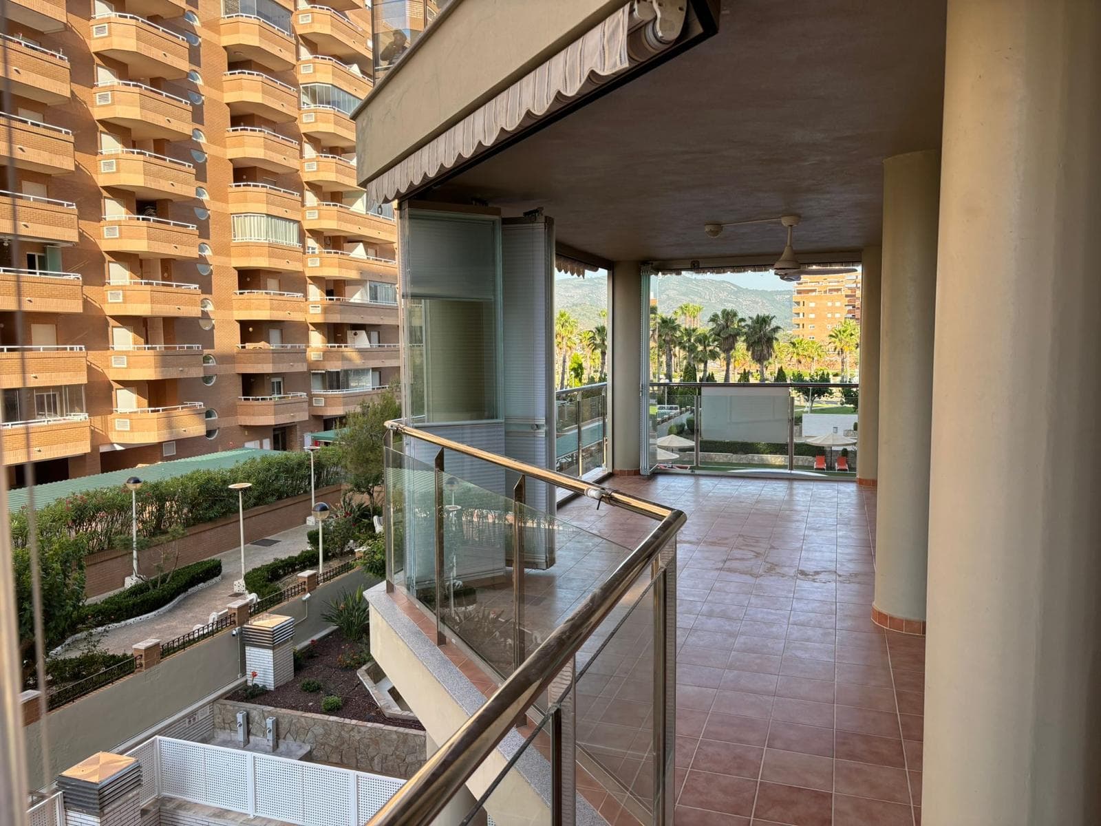 Cortina de cristal deslizante en balcón moderno con vistas y palmeras tropicales